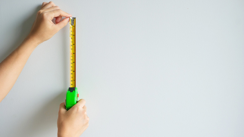 Woman measuring wall to hang wall art